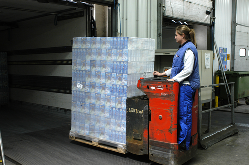 A woman steering a pallet of goods in a factory