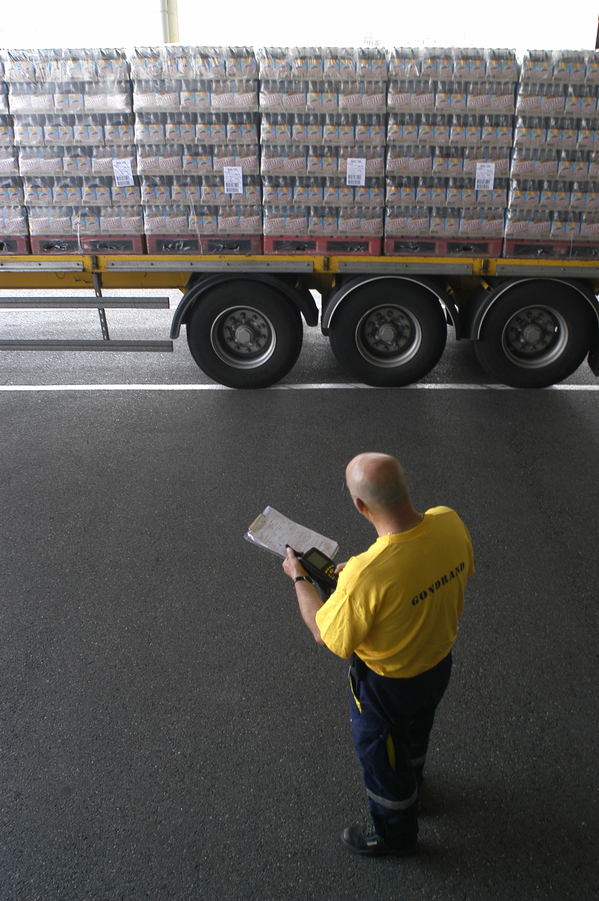 A man with a clipboard checks out a lorry load of product from the factory